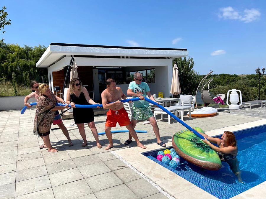 Colegi care trag de frânghie într-o probă lângă piscină