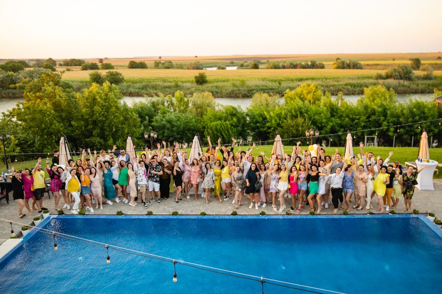 Grup mare de participanți lângă piscina Elysion View, cu lacul în fundal
